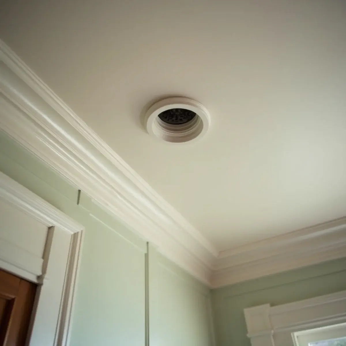 Small round high-velocity air outlet in the plaster ceiling of a historic home